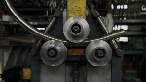 Industrial machine for cold metal pipe bending at industrial hall at manufacturing plant.